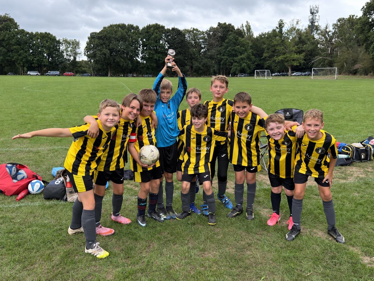 The Holland Sports Jaguars Under-10s in their yellow and black Huxley Surveyors kits, one player holding a trophy aloft