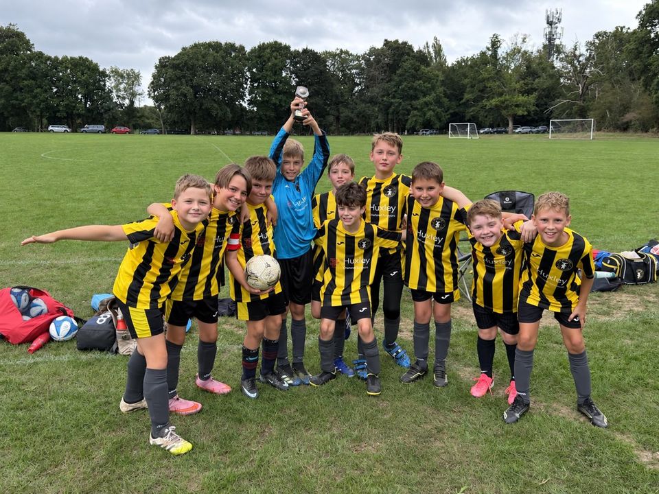 The Holland Sports Jaguars Under-10s in their yellow and black Huxley Surveyors kits, one player holding a trophy aloft